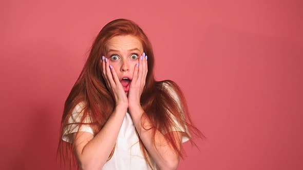 Scared Shocked Redhaired Ginger Woman in Pink Studio Background