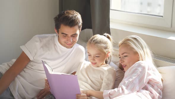 Friendly Parents Read Book Child Bed Before Going To Sleep Have Talk