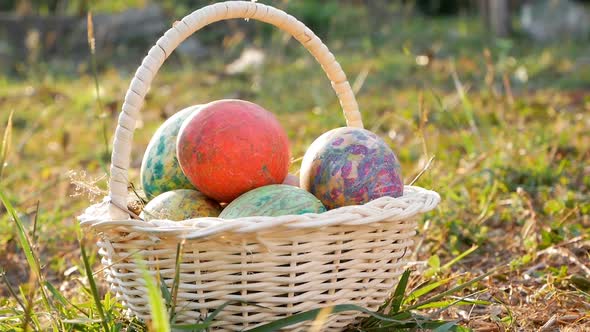 Close-up of basket with colourful a Easter eggs on grass in sunshine