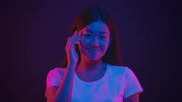 Young Positive Asian Woman Tapping on Temple Showing at Her Brain and Smiling to Camera in Bright