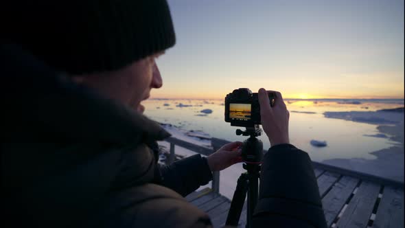 Photographer Looking At Screen Of Camera Of Sunset Over Sea