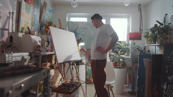 Male Artist Drawing Picture on Canvas in Studio