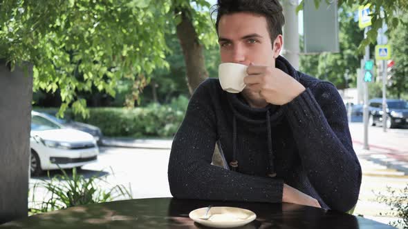 Young Man Drinking Coffee While Sitting in Cafe Terrace