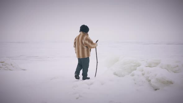 Wide Shot Winter Landscape with Indigenous Senior Man Walking with Stick in Slow Motion