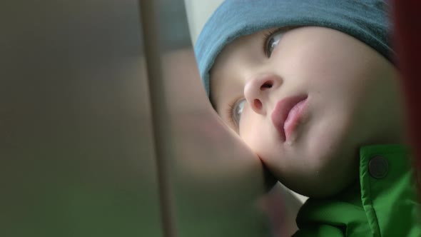 Close Up View of Small Boy Bored Face in Winter Hat on His Place in the Rail Train