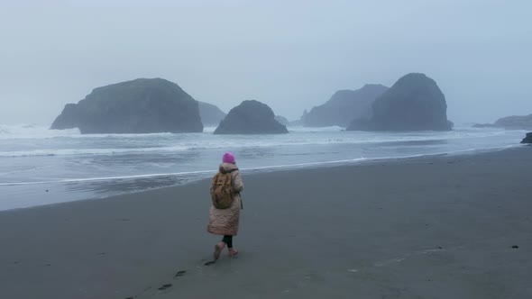 Traveler Woman Walking By Wet Ocean Beach Leaving Footprint on Sand Surface