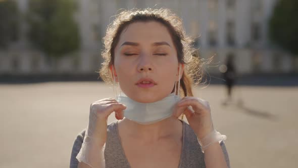 Young Asian Woman Portrait Takes Off Medical Mask at Sunny Day