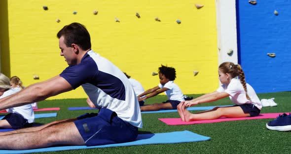 Yoga instructor instructing children in performing exercise