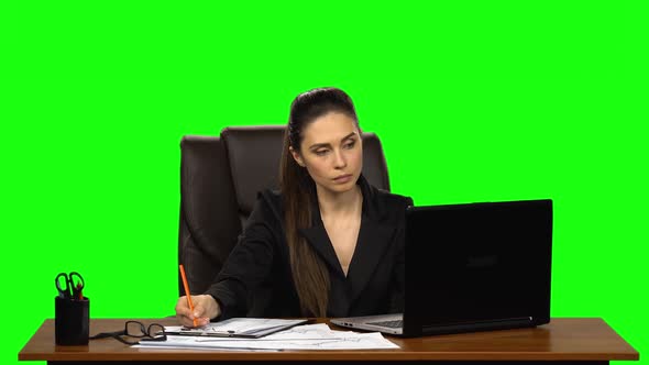 Female Manager Works on a Laptop, Think and Takes Notes. Green Screen Background