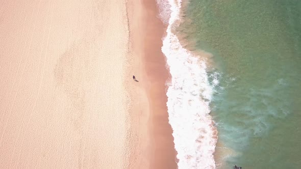 Bird eye view of beach activities during summer. Long aerial flight of clean sandy beach and clear o