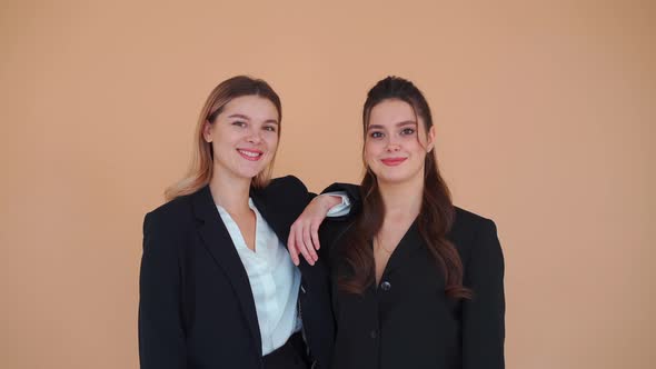 Two Young Business Woman Dressed Black Formal Suit Standing Studio Beige Background Looking Camera