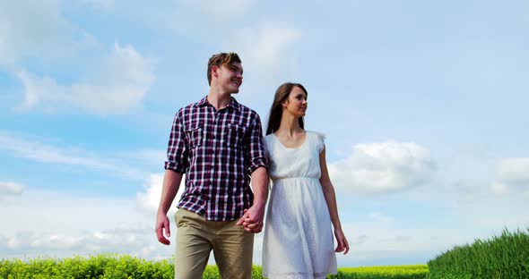 Romantic couple holding hands while walking in field