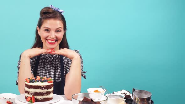 Happy Girl Pastry Chef Smiling at Camera While Sitting at the Table with Pastry