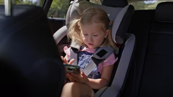 Video of little girl on rear seat of car with phone. Shot with RED helium camera in 8K.