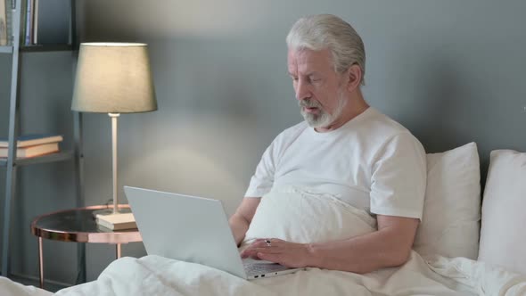 Handsome Old Man Using Laptop in Bed