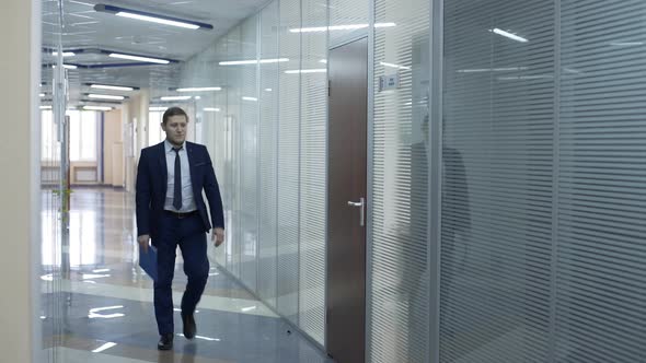 Caucasian Businessman in Black Suit Walking Along Corridor To His Office Room