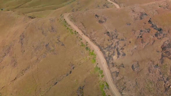 Aerial view following mountain bikers going down a mountain pass 60fps