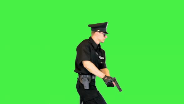 Young Caucasian Policeman Walks with Gun in Hands on the Alert on a Green Screen Chroma Key