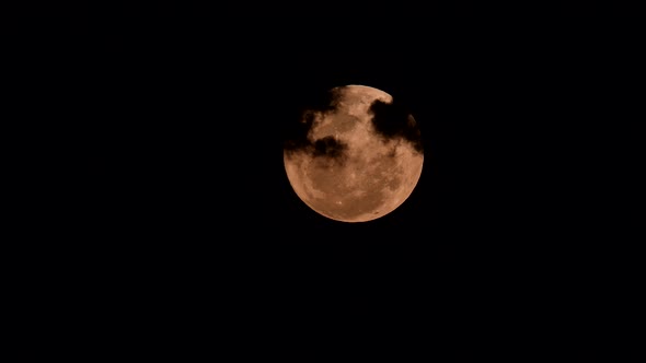 Full moon with clouds passing by .