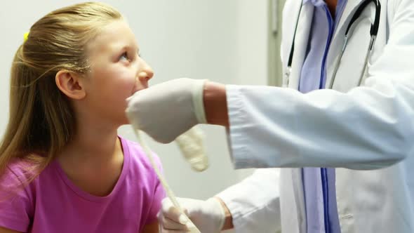 Female doctor putting bandage on injured hand of girl