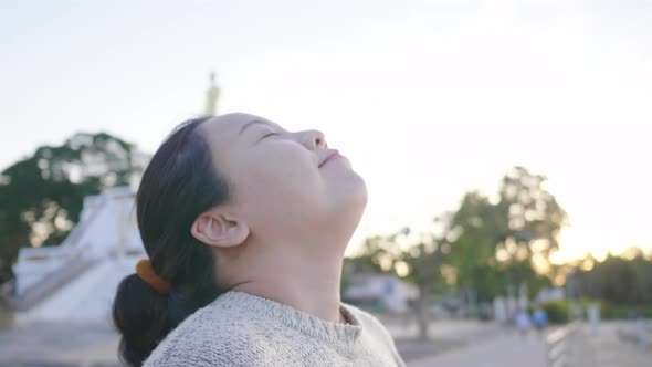 Close up of Asian woman standing and taking deep breath at park