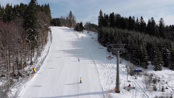 Aerial View of Skiers Go Down Ski Slopes Near Ski Lifts on Ski Resort. Bukovel