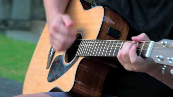 Close Up of a Young Man Playing Acoustic Guitar Outside