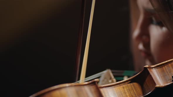 Closeup View of Violin and Face of Young Woman Musician is Playing Fiddle in Music School