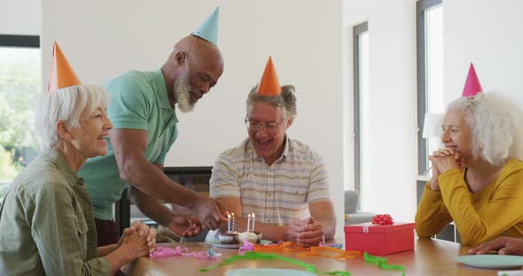 Happy senior diverse people at birthday party with cake at retirement home