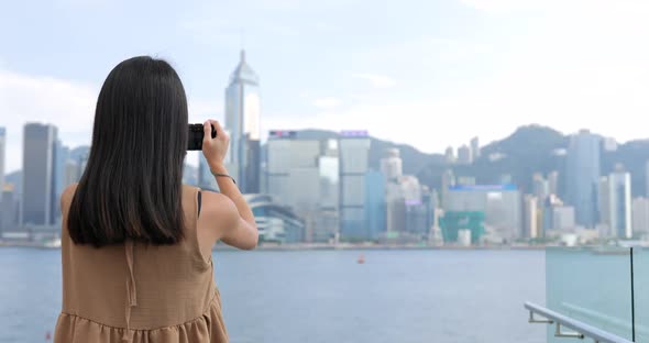 Young Woman taking photo with cellphone in Hong Kong Victoria harbor 