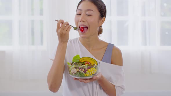 Healthy Young Asian woman eat mixture of vegetables Fresh Salad at home