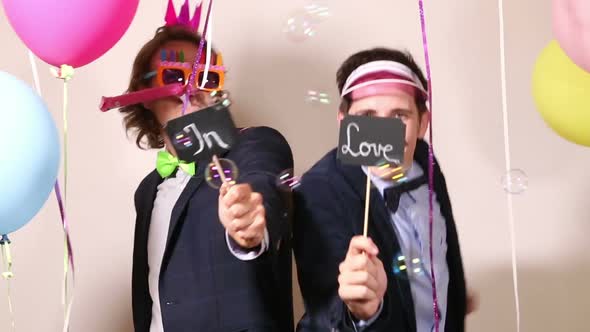 Funny male friends dancing with a sign in love in photo booth