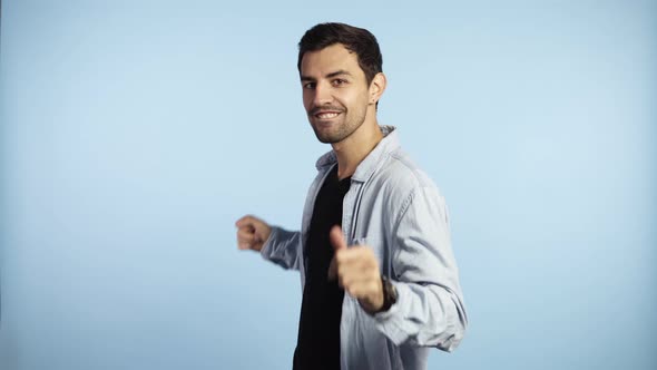 Cropped Portrait of Glad Caucasian Guy in Blue Shirt Fooling Around in Studio