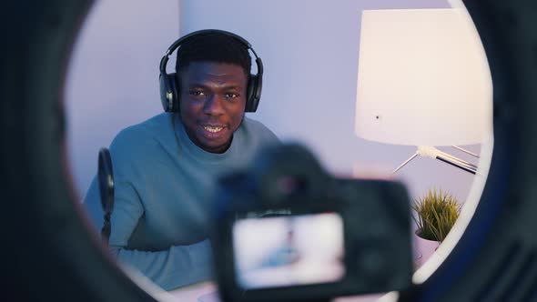 A Man Wearing Headphones Sitting at the Table Talking While Looking at the Camera