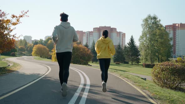 Man and Woman Running on a Track at the Park in Autumn Talking and Smiling