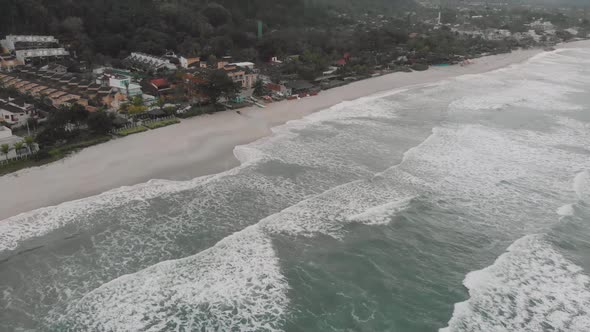 Drone footage of the beach above the sea, mountain in front of the sea, cloudy day, waves, landscape