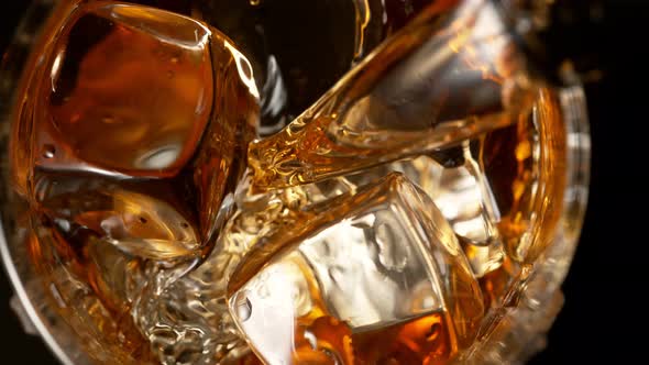 Super Slow Motion Detail Shot of Pouring Whiskey on Ice Cubes Into Glass at 1000Fps
