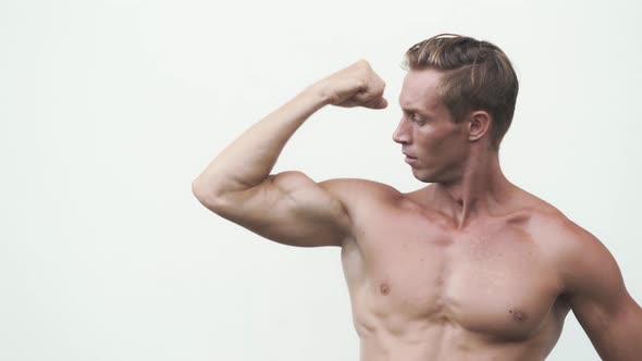 Shirtless Man Shows Muscular Pumped Up Biceps on His Arm, White Background