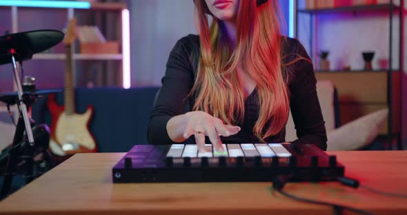 Female DJ Artist in Headphones Creating New Music on Drum Pods Midi Equipment in Home Studio
