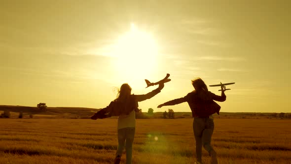 Dreams of Flying. Happy Childhood Concept. Two Girls Play with a Toy Plane at Sunset