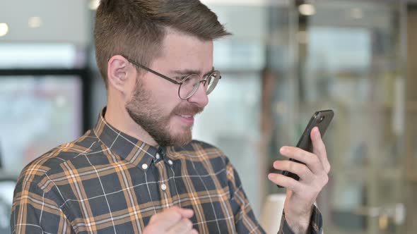 Portrait of Young Designer Celebrating Success on Smartphone