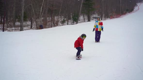 Young Man Snowboard Instructor Tiches Little Boy How To Ride a Snowboard. Winter Activities Concept