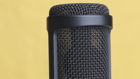 Studio Condenser Microphone Rotates on Yellow Background with Place for Text