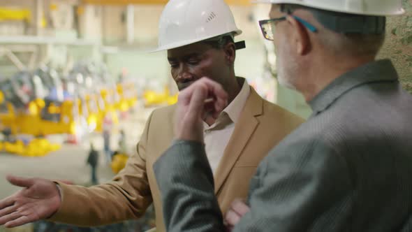 African American Engineer Speaking with Colleague in Factory