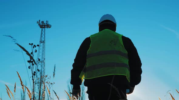 Silhouette Engineer Working on Satellite Dish Telecom Network on Telecommunication Tower in Sunset