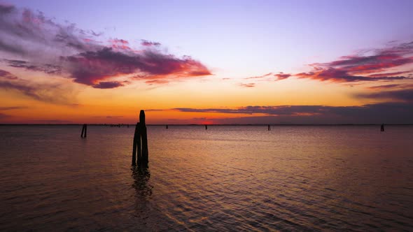 Dark Pillar Silhouettes in Rippling Lagoon at Sunset