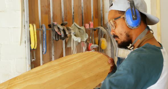 Surfboard maker examining surfboard 