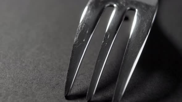 Elegant steel fork with black shadow on a dark table. Art restaurant serving