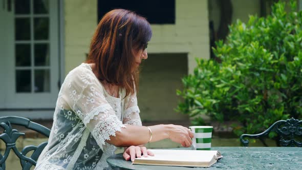 Mature woman having coffee while reading a book 