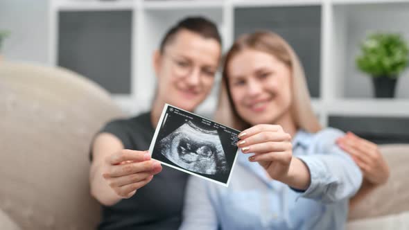Happy Pregnant Homosexual Female Couple Smiling Feeling Love Showing Embryo Ultrasound Image Card
